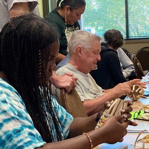 people in a classroom making woven baskets from wood